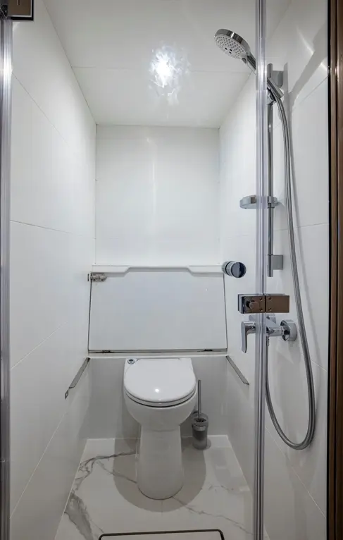 Compact bathroom featuring a shower, toilet, and marble effect flooring in a modern design with neutral tiles.